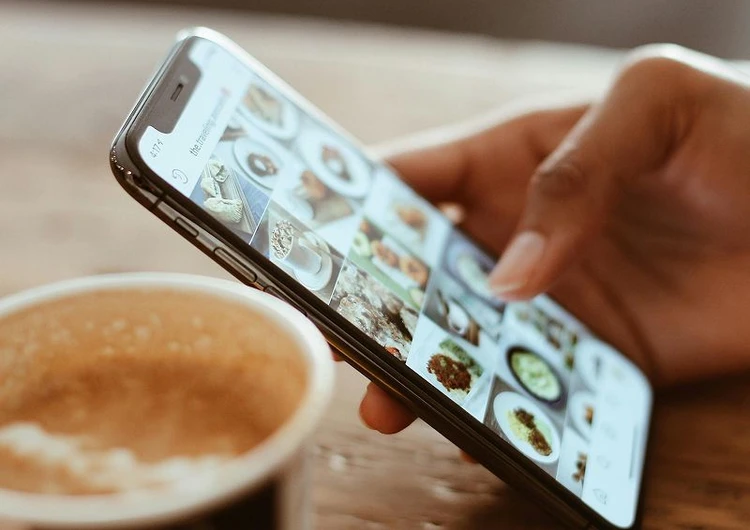 mano con cellulare e tazza di caffè