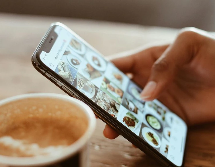mano con cellulare e tazza di caffè
